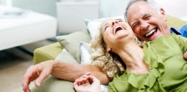 A picture of a male and female laughing on a couch